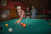Person playing pool in a bar with two other people watching while wearing Richardson 5-Panel Relaxed Gramps Caps - the 356