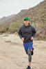 Person running outdoors in a desert landscape wearing a Nike hoodie and blue shorts with a Lucky Green Dri-FIT Swoosh Performance Cap