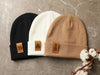 Laser engraved leather fold over tags sewn to a beanie