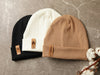 Laser etched narrow leather tags applied to beanies with rivet snaps.